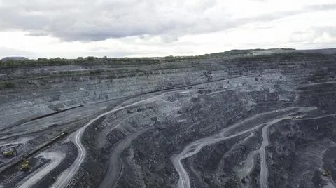 Coal mining at an open pit. Top view of the quarry. Dozers and trucks at Stock Photos