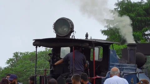 Coal steam engine operator on toy train looking around at the crowd of people Stock Footage 249166625