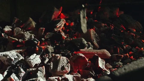 Coals inside the brazier are mixed with a metal poker. 4k Stock Footage 112061821