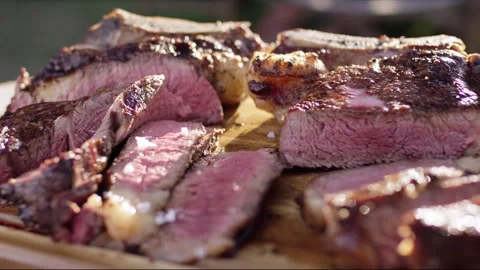 Coarse salt falling onto freshly grilled sliced steak with pink center on a Vídeo Stock 339954380