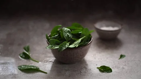 Coarse salt falling on Leaves of fresh baby spinach Stock Footage 160414293