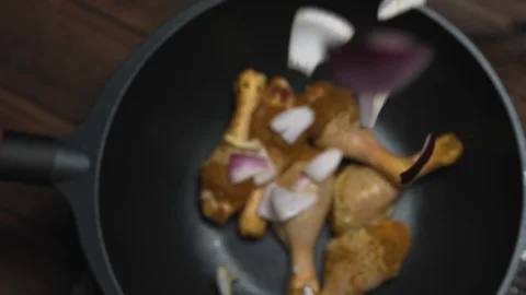 Coarsely chopped purple onion falling in wok with pickled chicken, top view Stock Footage 123572869