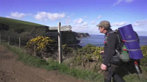 Coast to coast path, hiker touching signpost near robin hood's bay Stock Footage 342201877