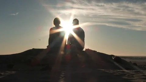 Coast Couple Sit Watching Sunset From Beach Stock Footage 80675527