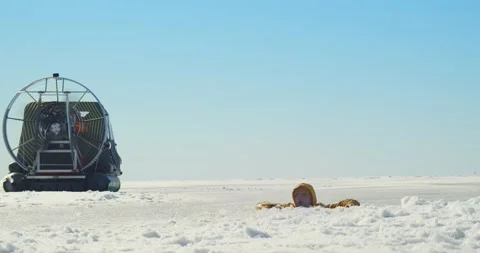 Coast guard team on hovercraft rescuing man fallen though ice Stock Footage 152155529