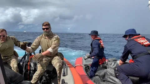 Coast Guard transfer bales of seized cocaine from interceptor boat Stock Footage 120079751