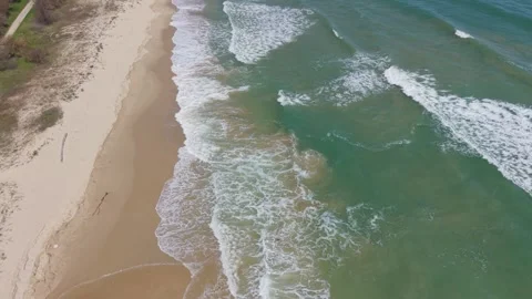 Coastal aerial waves rolling onto sandy beach shoreline scene Stock Footage 332938861