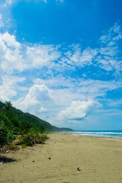 Coastal beach with distant hill  under blue sky Stock Photos