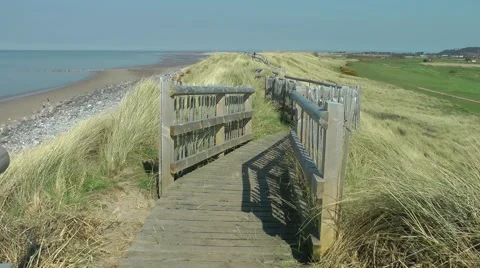 Coastal boardwalk path sand dunes sea blue sky Stock Footage 49437467