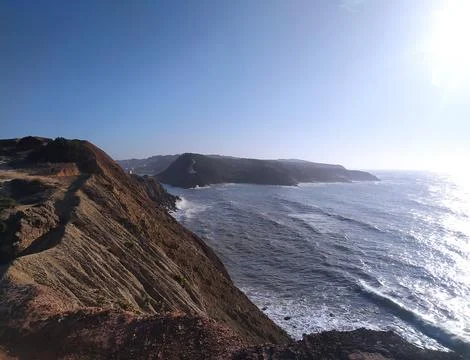 Coastal cliff view of rough waves crashing against the rocks in the afterno.. Stock Photos