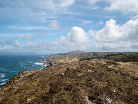 Coastal cliffs and ocean under cloudy sky Stock Photos