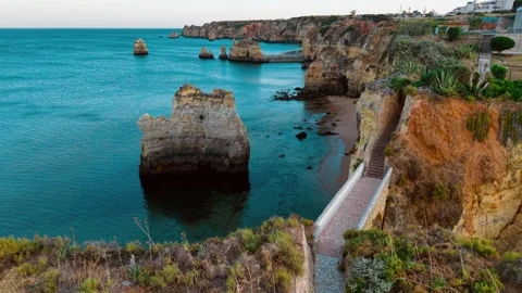Coastal cliffs and turquoise waters in Algarve, Portugal during sunset Stock Footage 312326232
