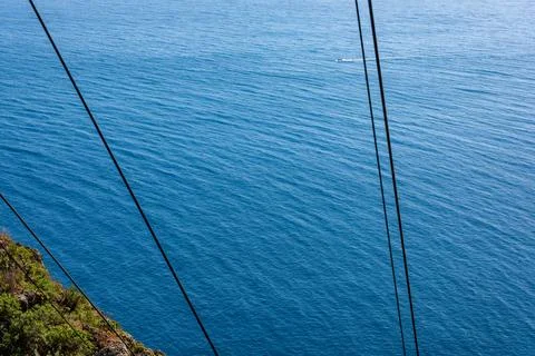 Coastal Cliffs with Power Lines Over Blue Ocean in Madeira Foto stock
