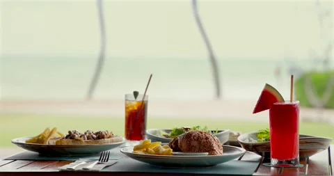 Coastal dining table with delicious meals and fruity drinks, beach Stock Footage 311998480