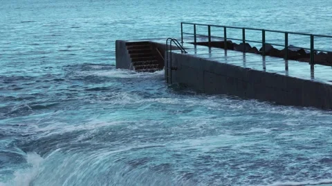 Coastal footage capturing waves hitting a concrete pier with rhythmic Stock Footage 346889359