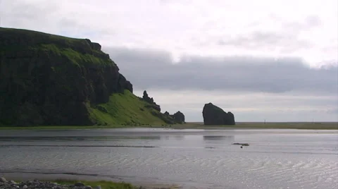 Coastal lagoon in front of beach by cliff and fast clouds Stock Footage 37685901