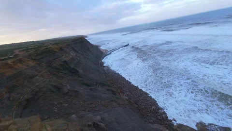 Coastal landscape with cliffs, path, and frothy ocean waves at twilight Stock Footage 344674491