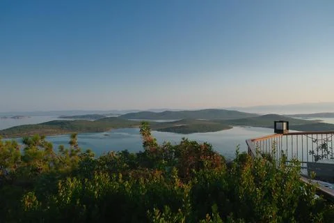 Coastal landscape with pine trees overlooking calm water and distant islands Stock-Fotos