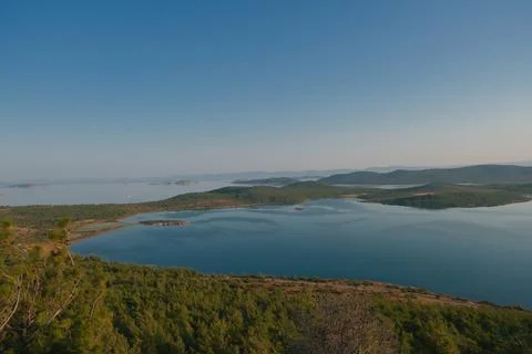 Coastal landscape with pine trees overlooking calm water and distant islands Stock-Fotos