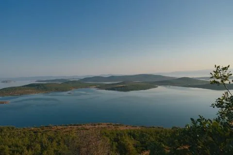 Coastal landscape with pine trees overlooking calm water and distant islands Stock-Fotos