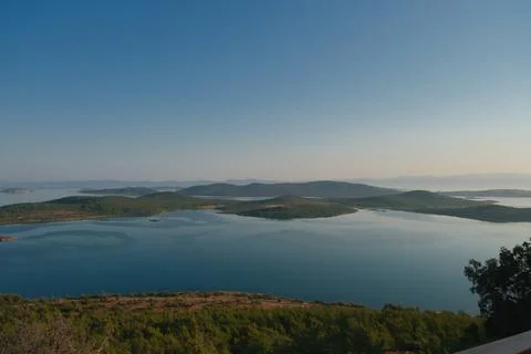 Coastal landscape with pine trees overlooking calm water and distant islands Stock-Fotos