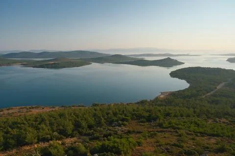 Coastal landscape with pine trees overlooking calm water and distant islands Stock-Fotos