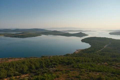 Coastal landscape with pine trees overlooking calm water and distant islands Stock Photos