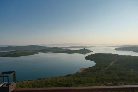 Coastal landscape with pine trees overlooking calm water and distant islands Stock-Fotos