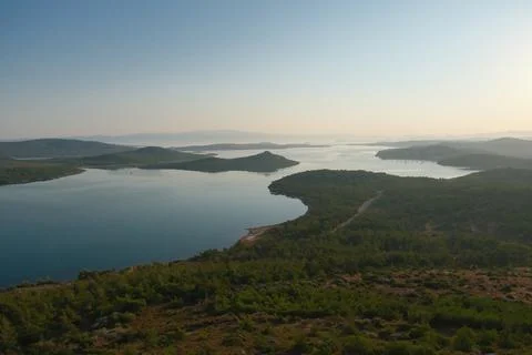 Coastal landscape with pine trees overlooking calm water and distant islands Stock-Fotos