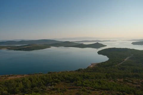 Coastal landscape with pine trees overlooking calm water and distant islands Stock-Fotos