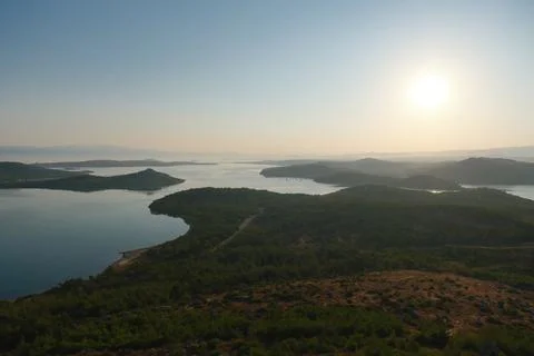Coastal landscape with pine trees overlooking calm water and distant islands Stock-Fotos