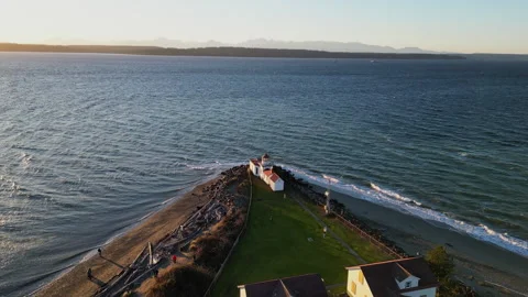 Coastal Lighthouse at Sunset with Mountain Range in the Background 動画素材 283434073