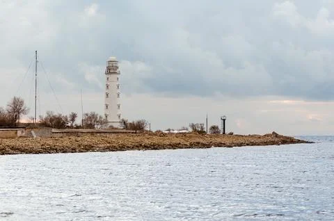 Coastal lighthouse under cloudy sky with calm seascape Stock Photos