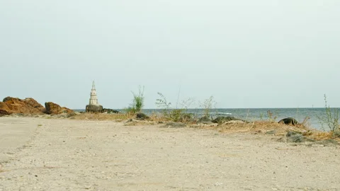 Coastal path leading toward lighthouse by the sea on rocky shoreline 스톡 동영상 331870673