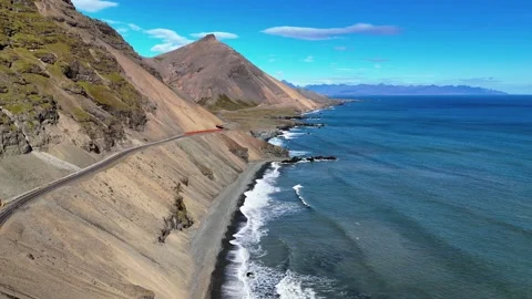 Coastal Road Beneath Rugged Mountains Along Iceland's Blue Sea Stock Footage 342268681