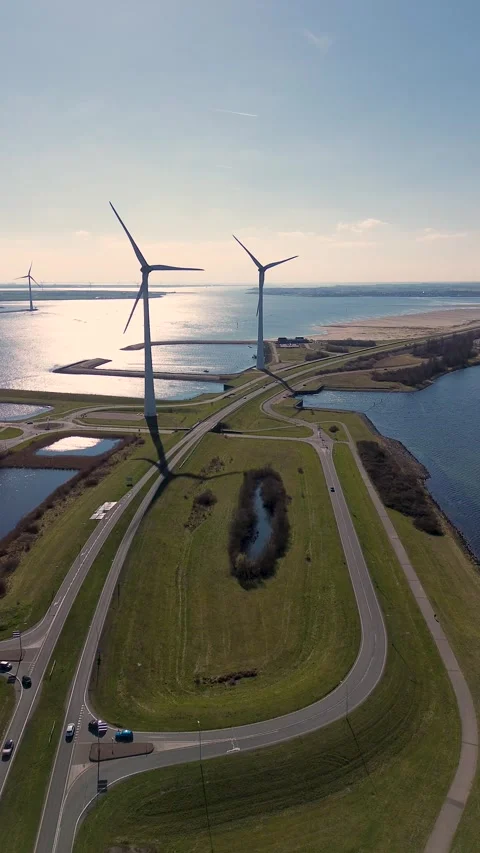 A coastal road runs between two bodies of water, lined with wind turbines Vidéo 304674695