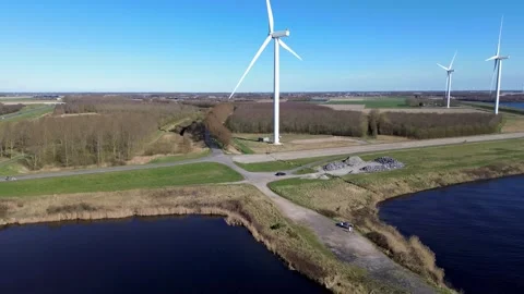 A coastal road runs between two bodies of water, lined with wind turbines Video stock 305908706