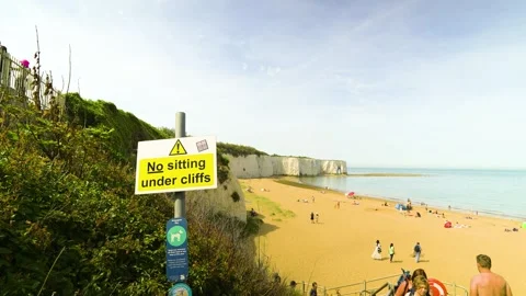 Coastal safety warning sign overlooking a beautiful sandy beach and towering Vídeos de archivo 346883294