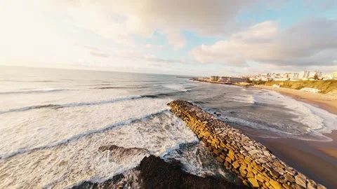 Coastal scene with breaking waves, cliffs, and cityscape under soft sunlight Stock Footage 340913770