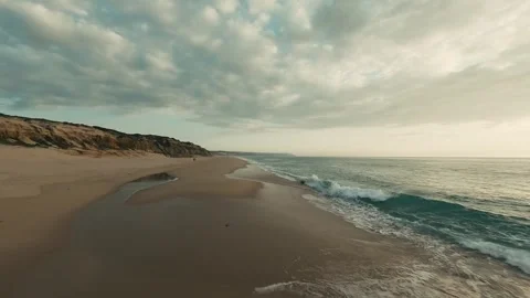 Coastal scene with soft waves, sandy beach, and hazy sky Stock Footage 340227331