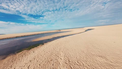 Coastal scene: sunlit dunes, shallow tide pools, and turquoise sea Video stock 340904659