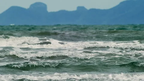 Coastal Surf Rolling Toward Distant Island Under Hazy Sky Видео 336303481