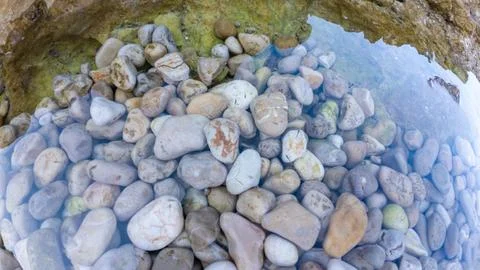 Coastal tide pool with smooth pebbles beneath clear water Stock Photos