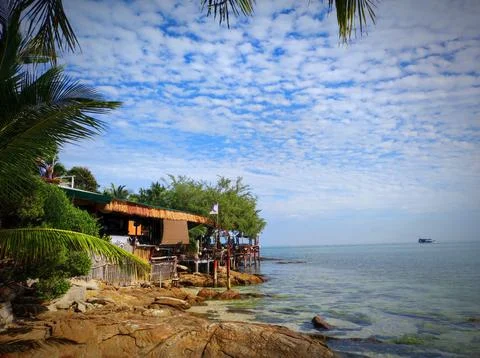Coastal view of a beachside restaurant surrounded by palm trees during a su.. Stock Photos