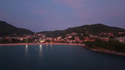 Coastal view of beachside town at dusk with illuminated buildings and water Stock-Footage 342312713