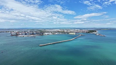 Coastal view of a busy port near a city with ships, docks, water, and clouds in Stock Footage 337942853