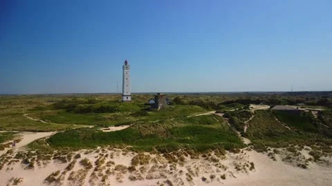 Coastal view of lighthouse on sandy beach during clear day near nature trai.. Stock Footage 339940392