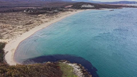 Coastal view of a sandy beach surrounded by gentle waves and hills Stock Footage 325720425