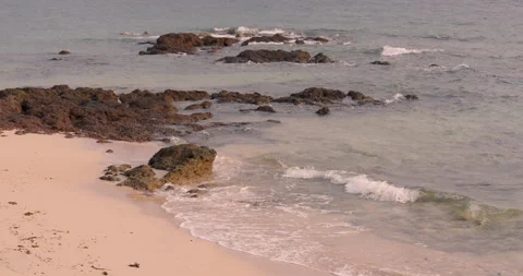 Coastal waves gently rolling onto rocky shoreline with clear ripples flowing Stock Footage 307611877