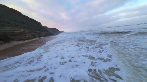 Coastline at sunrise, waves roll in, cliff backdrop Stock Footage 344673079